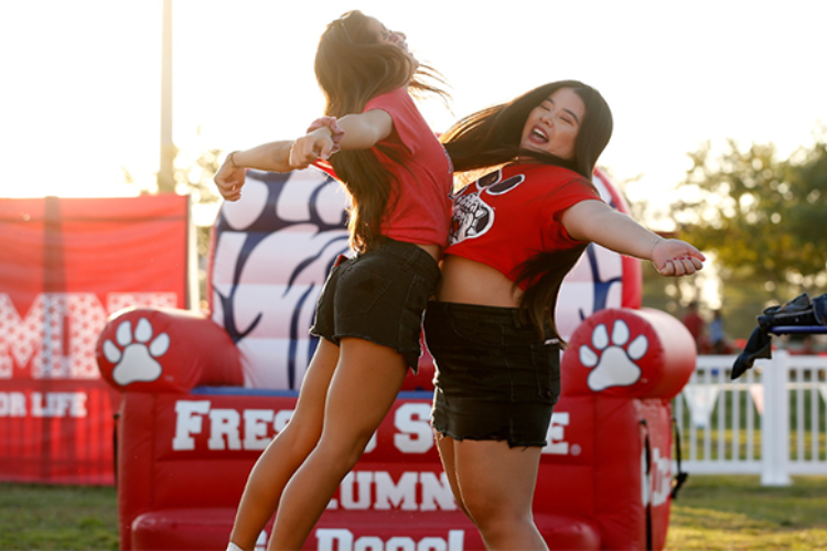 Two students doing a chest bump at Fresno State event. Click to get notified for ticket sales.