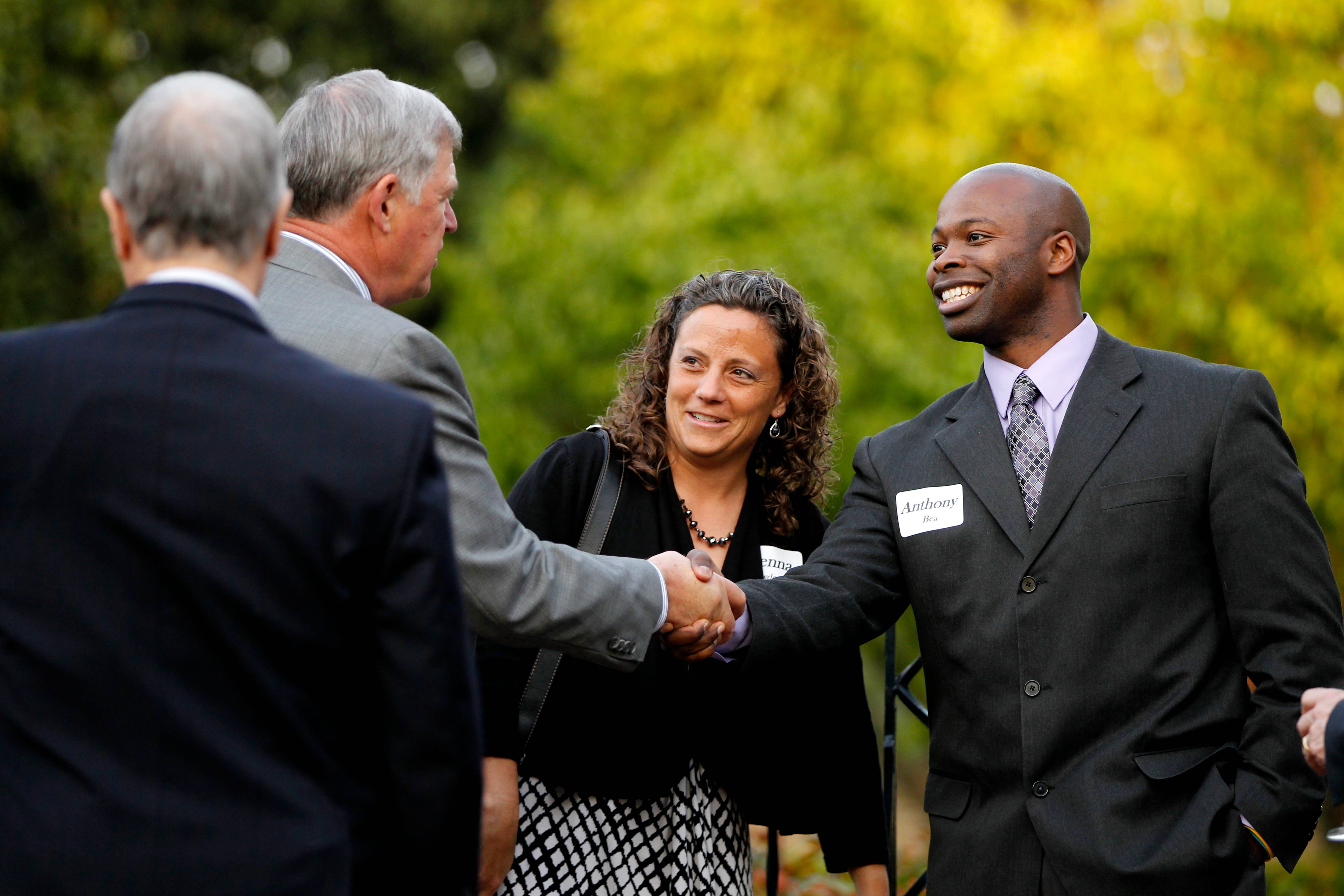 A gentleman shakes hands with a colleague during a campus visit.