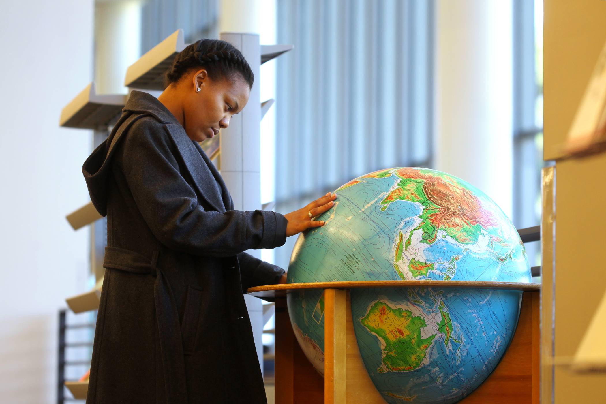 A woman touches a large and colorful globe to admire the map.