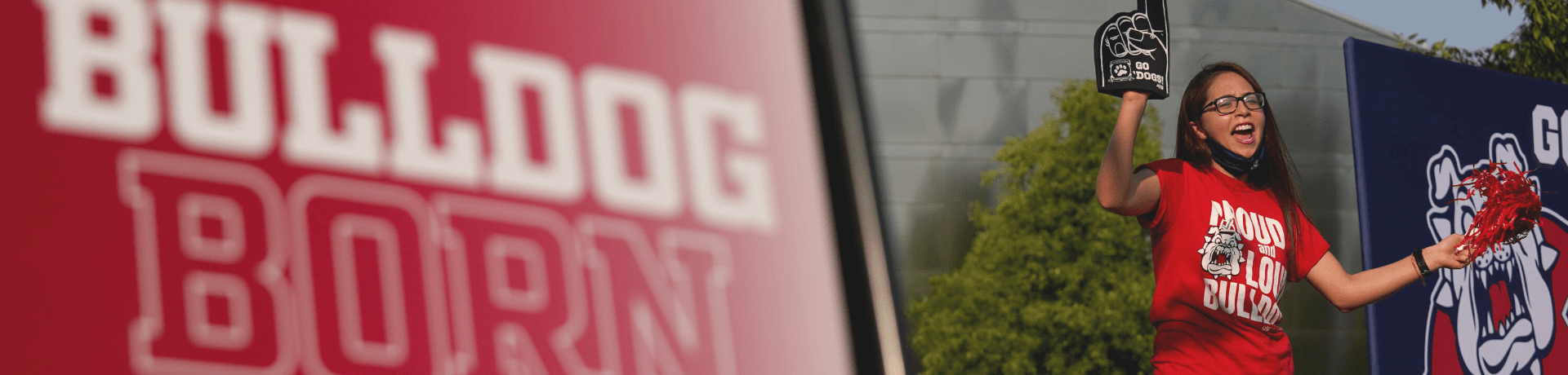Student cheering at event with Bulldog Born sign
