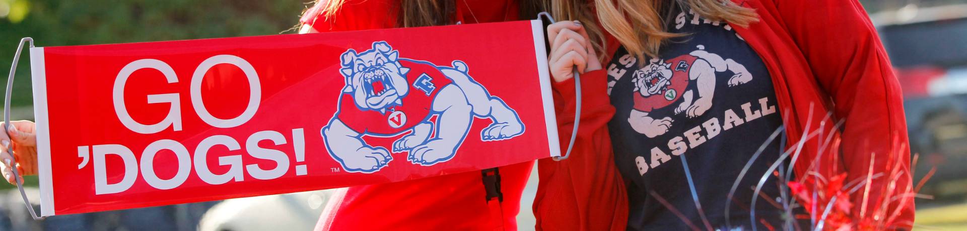 Two alumni hold a Fresno State banner.